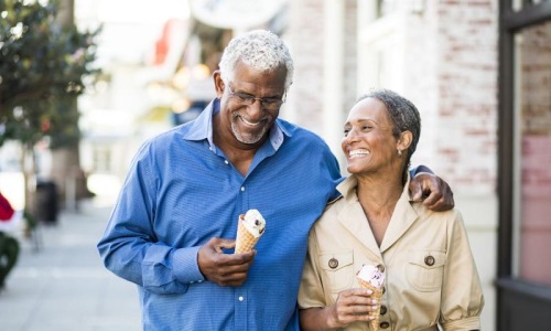 Close to the center of everything older couple walks down city sidewalk while holding ice cream cones